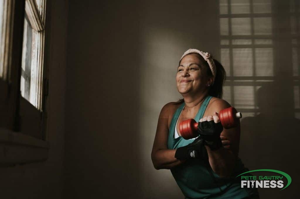 A calm, capable woman in her 40s training with dumbbells — the ordinary fundamentals, not fear, are what change your body