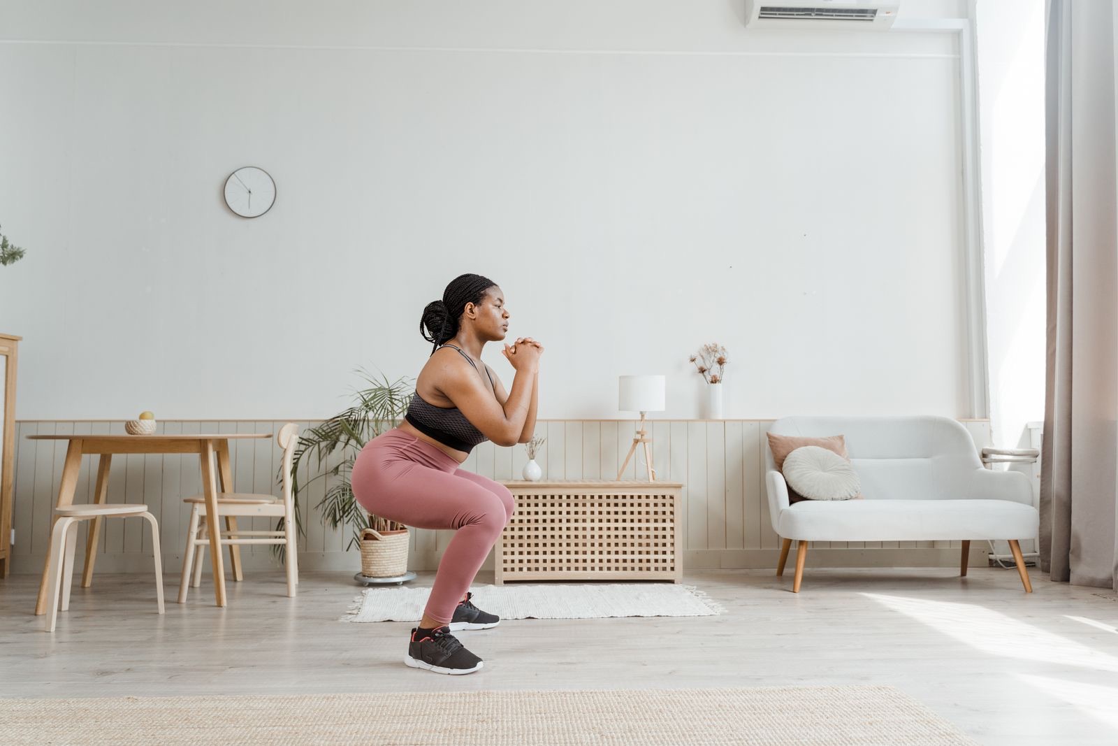 A woman doing bodyweight squats in her living room in everyday clothes
