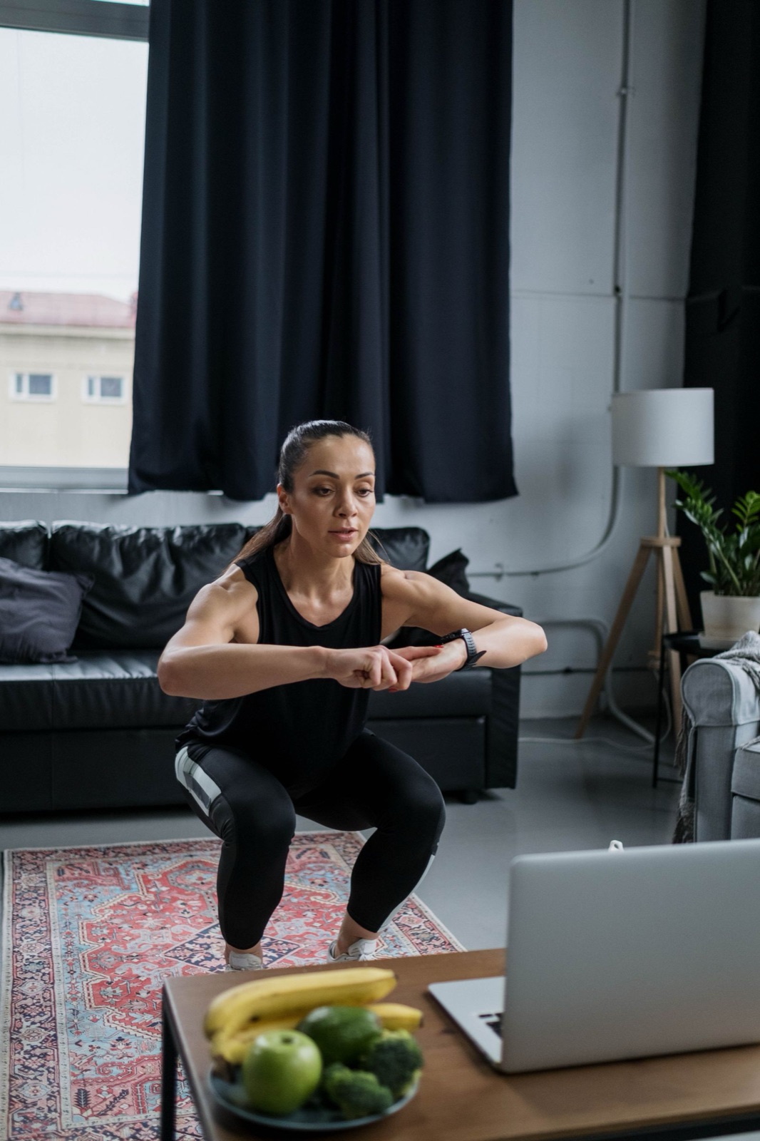 A woman squatting in front of her laptop at home between calls