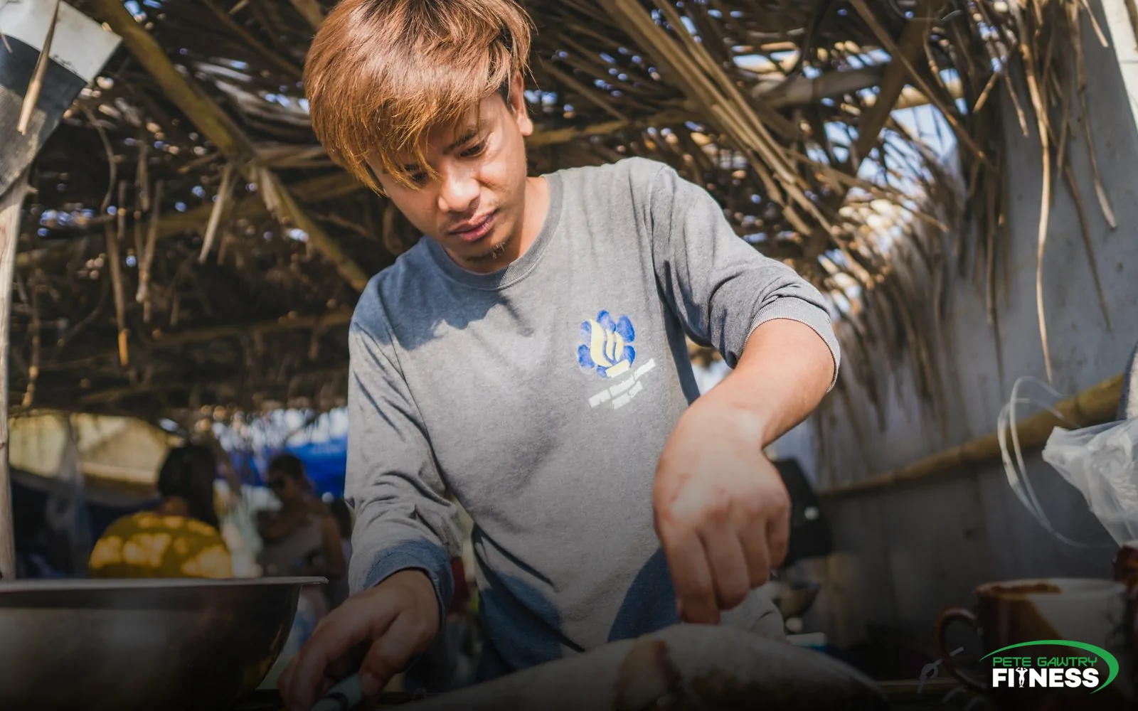 A man preparing fresh fish in an open kitchen — everyday food is where most of the load quietly comes from
