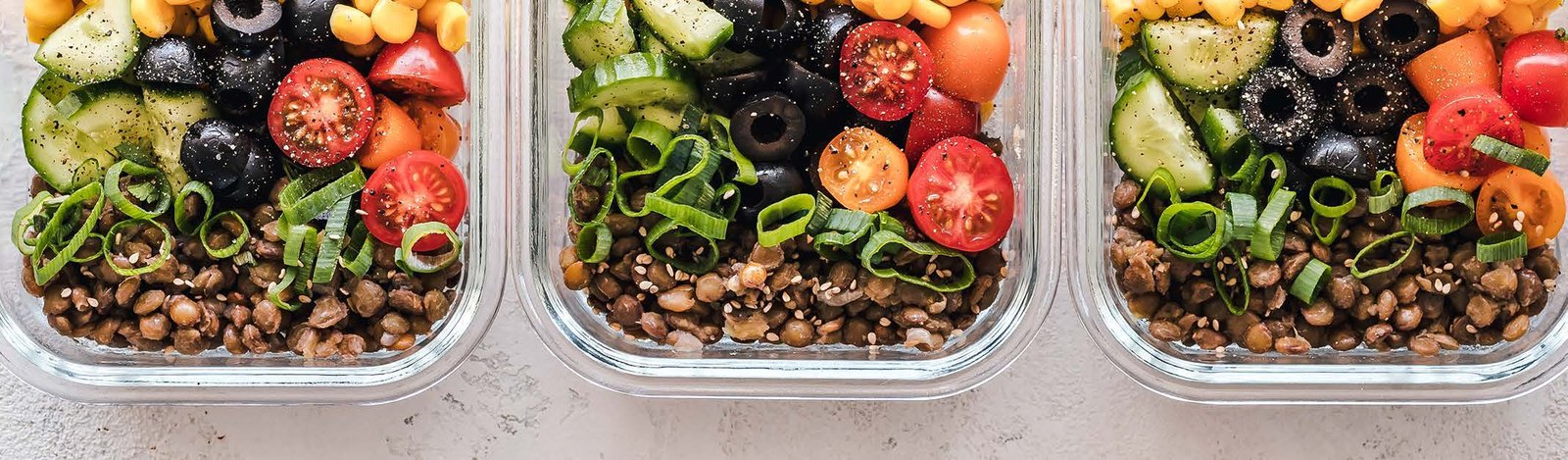Meal prep containers with lentils, vegetables and whole foods