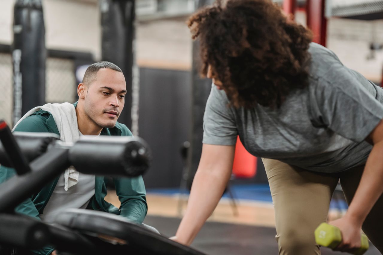 Personal trainer coaching a client through an exercise in the gym