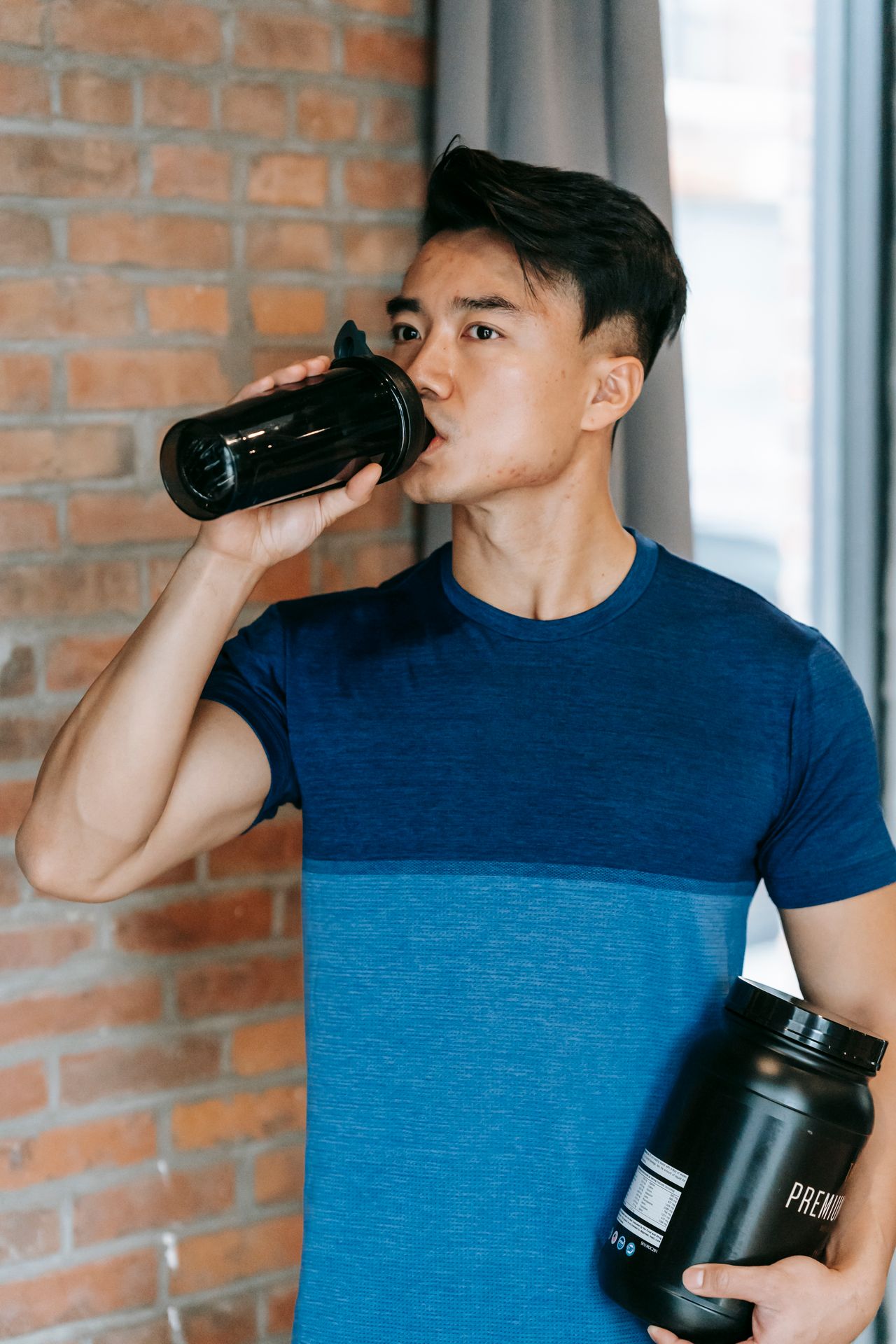 Fit man holding a supplement container after a workout in the gym