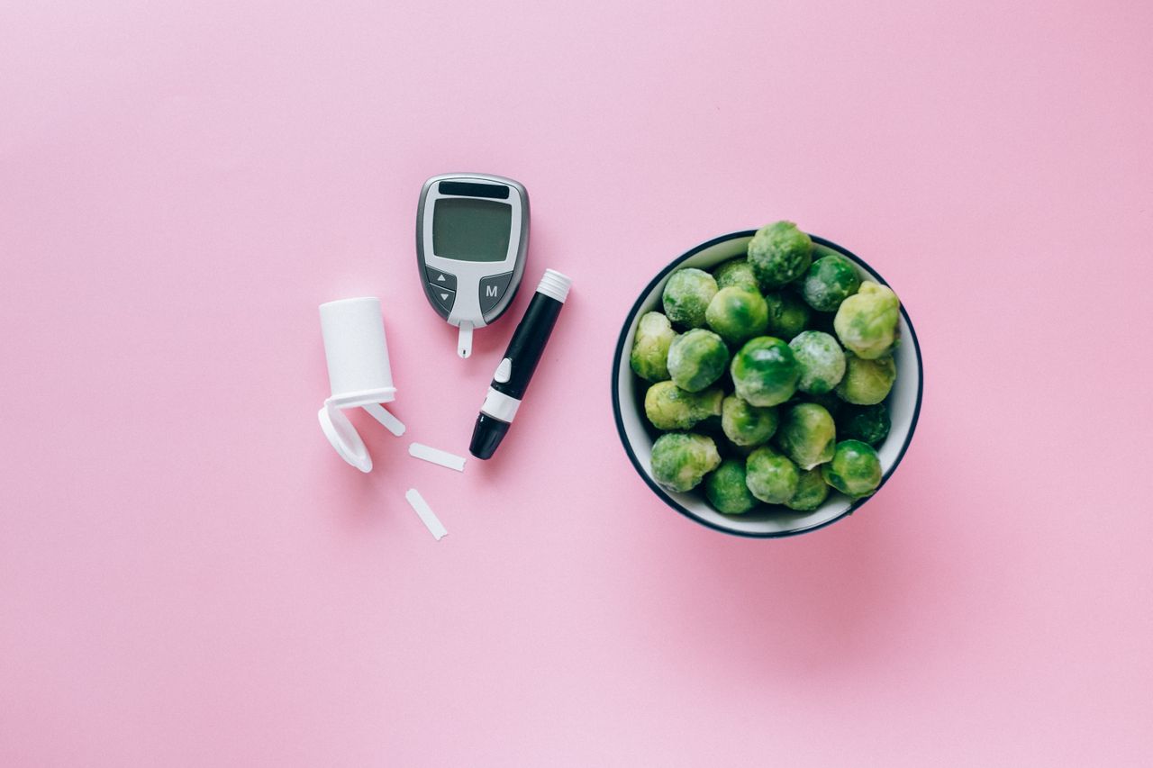 Blood glucose monitor beside fresh healthy vegetables