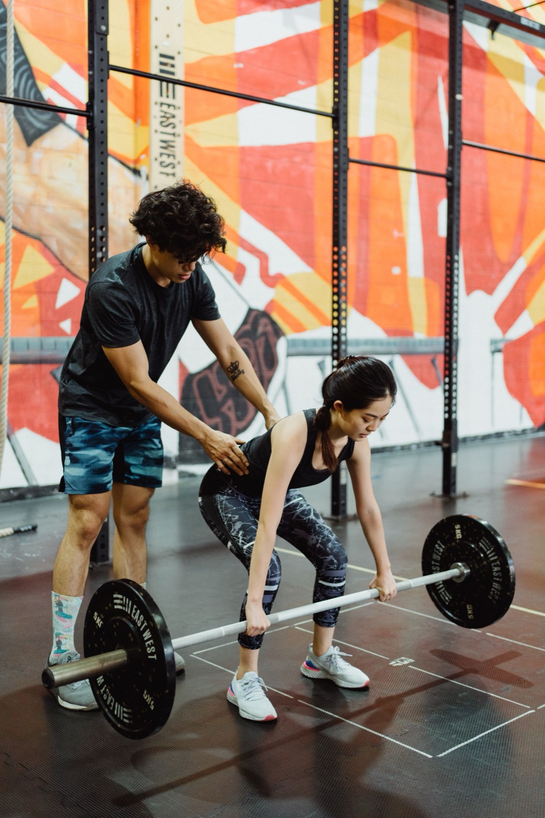 A coach correcting a client's set-up position at the barbell