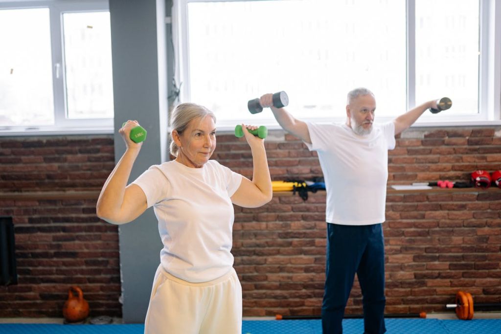 Older man and older woman lifting dumbbells together in a gym
