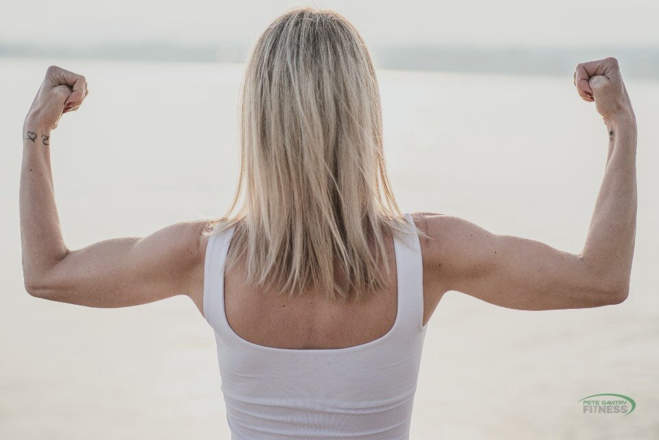 A woman flexing both arms, seen from behind