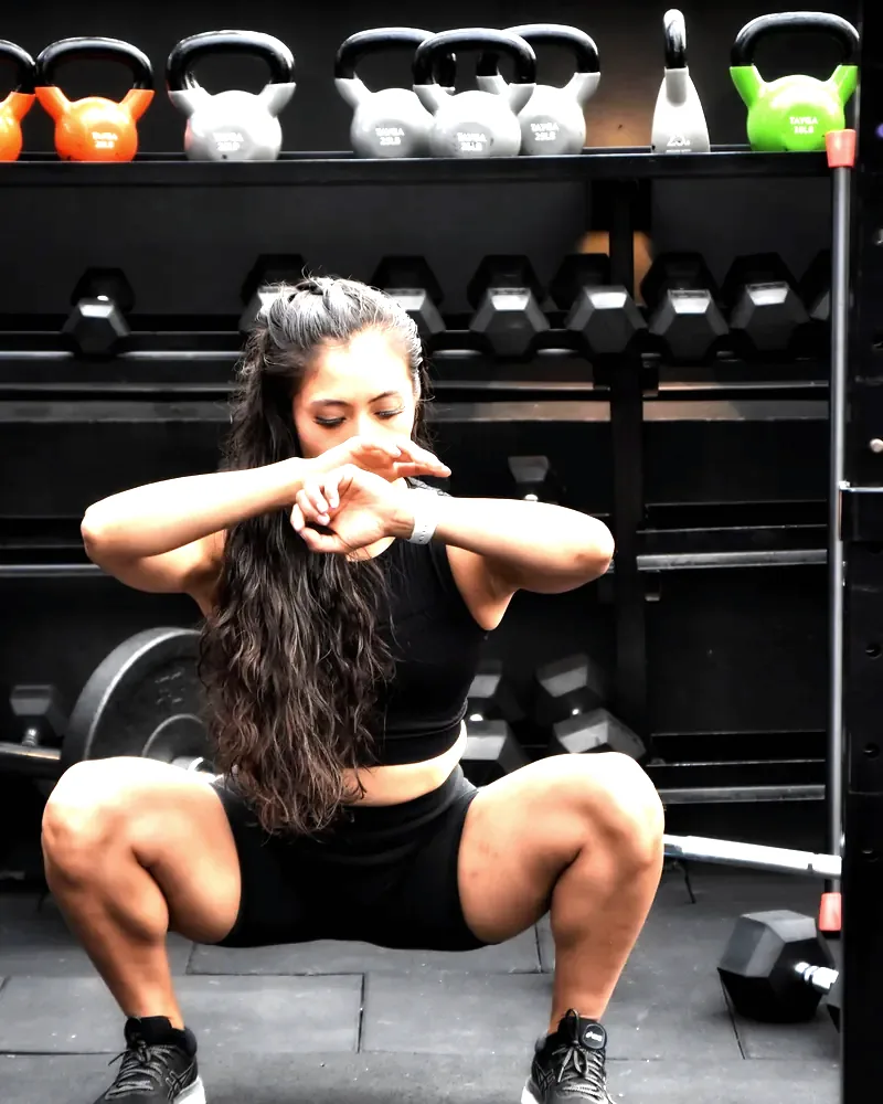 Kettlebell squat in front of a loaded rack