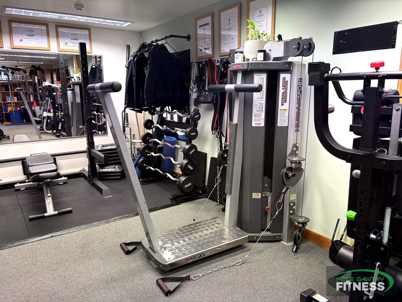 Plate-loaded belt squat standing platform machine and branded jackets at Pete Gawtry Fitness