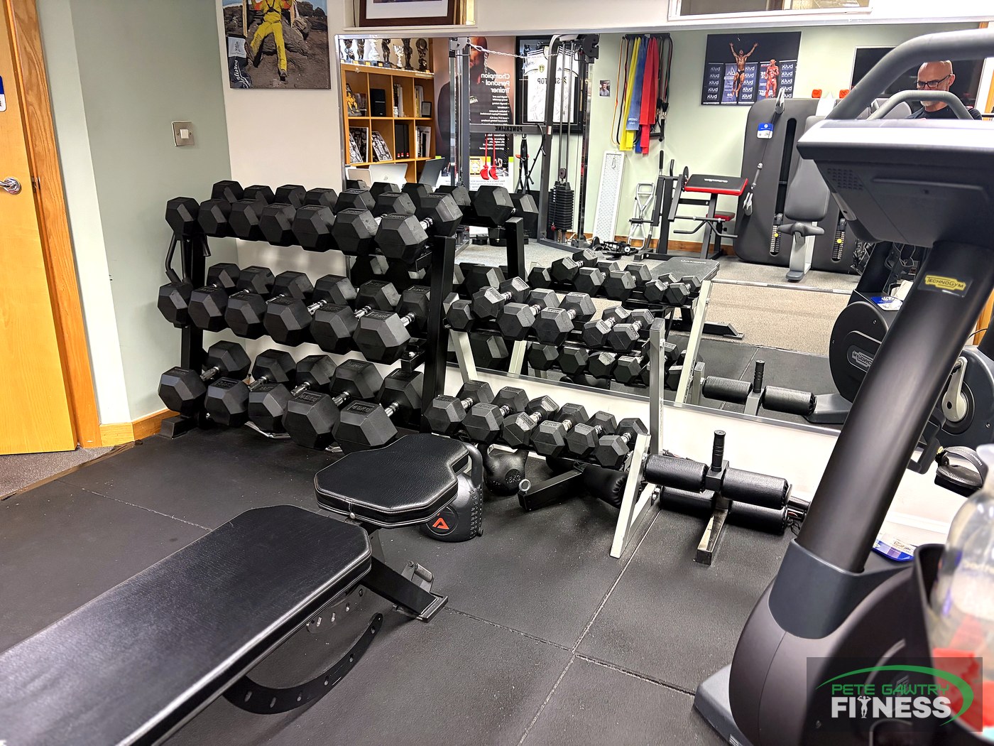 Three-tier hex dumbbell rack, flat bench and exercise bike inside Pete Gawtry's private fitness studio