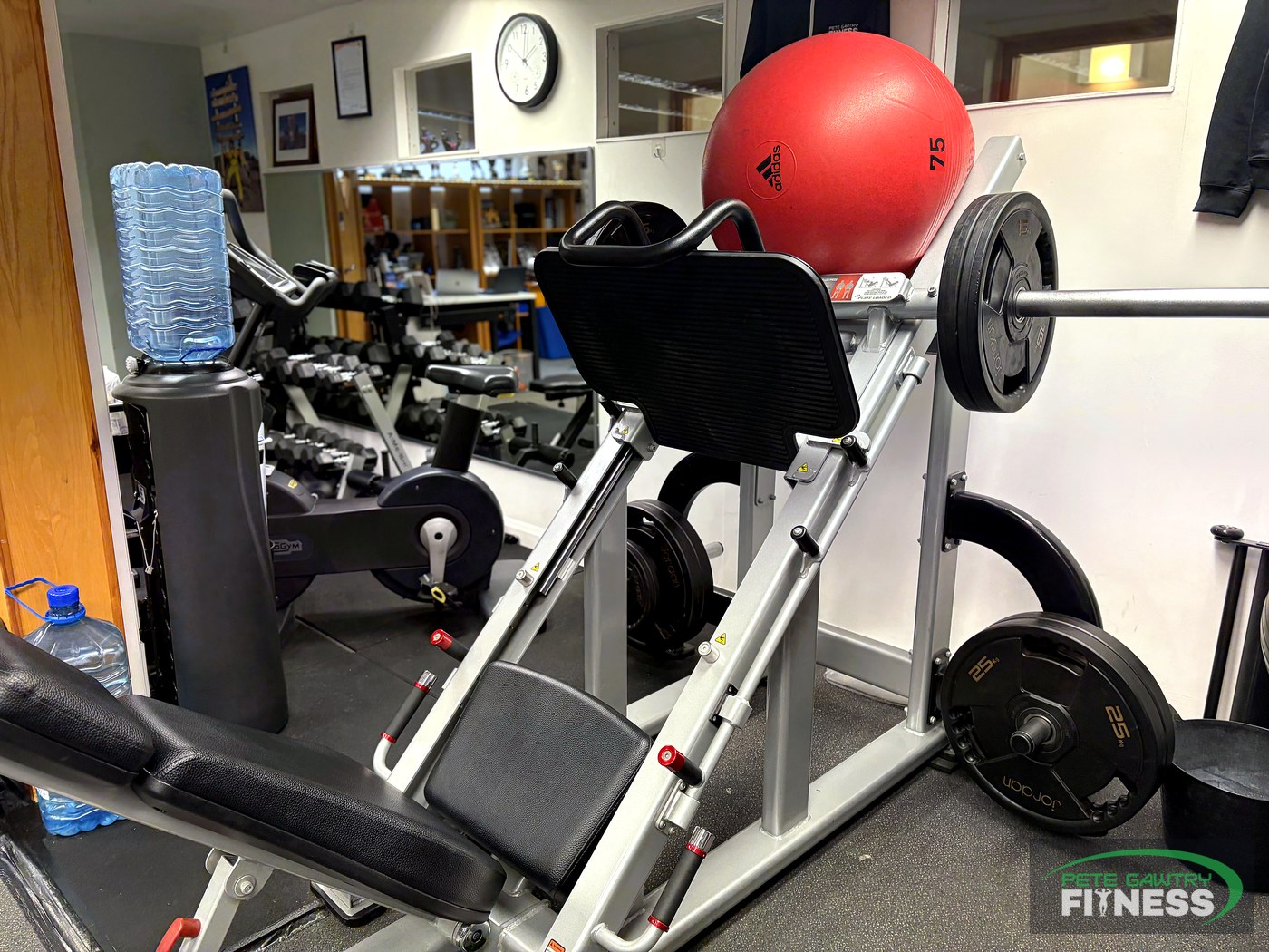 Plate-loaded leg press and hack squat machine loaded with Olympic plates at PG Fitness studio