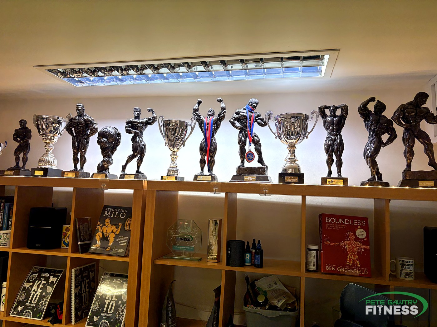 Shelf of bodybuilding trophies, cups, medals and fitness books at Pete Gawtry Fitness studio